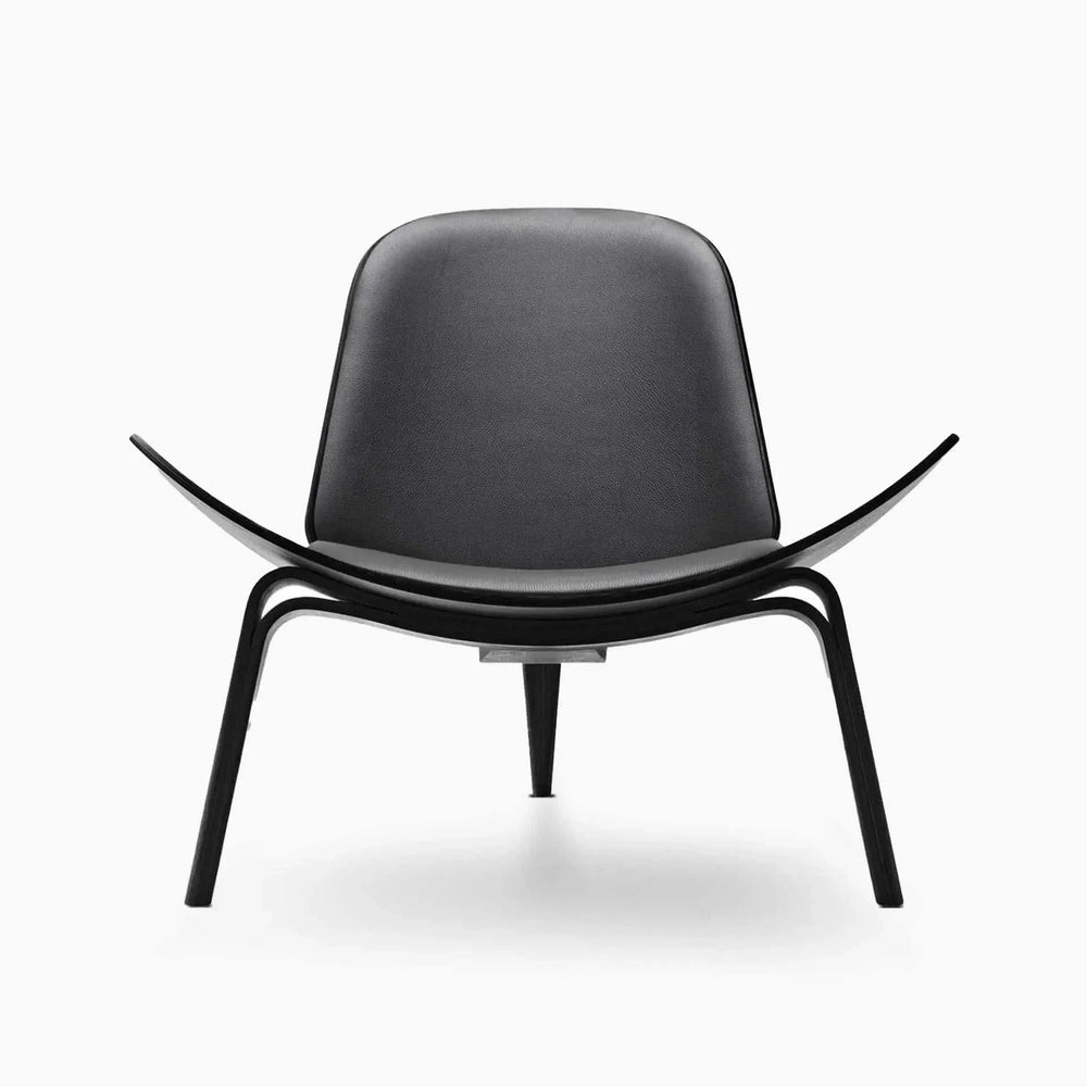 Elegant Shell Chair in black leather and walnut finish in stylish interior setting.