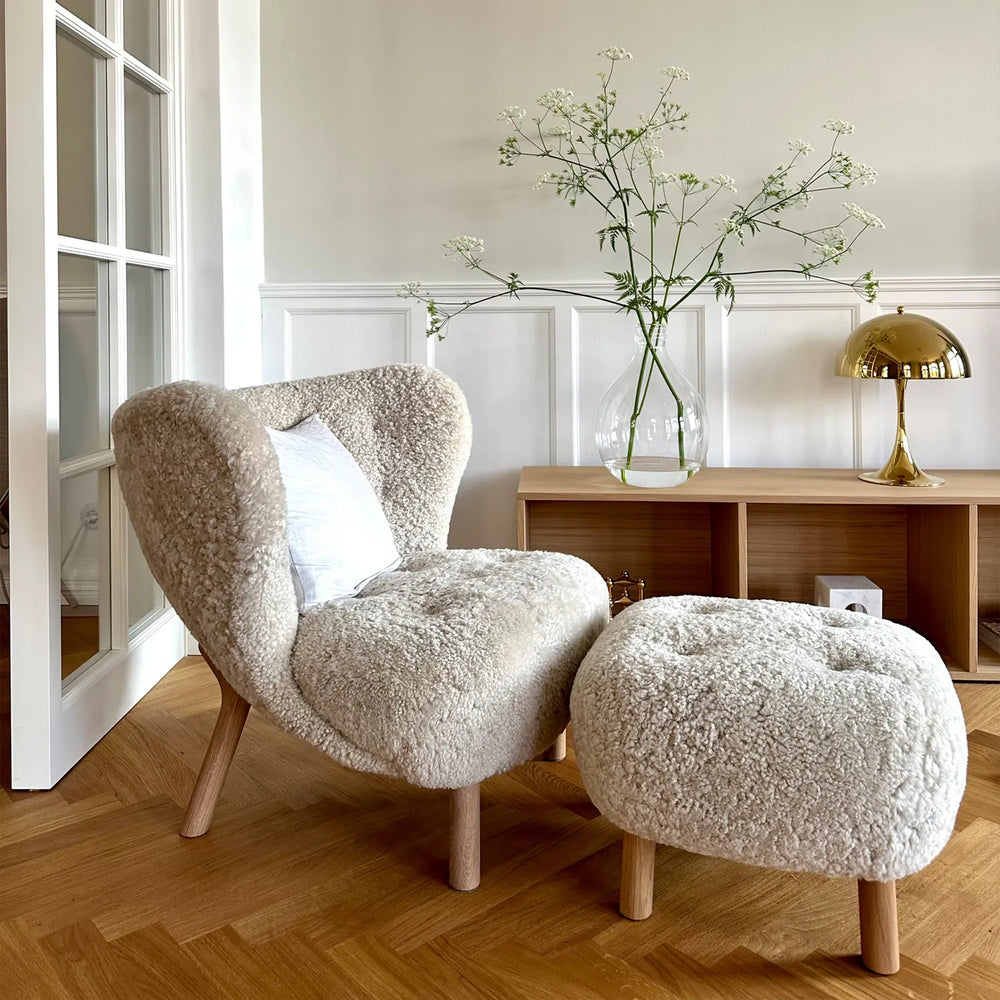 Little Petra Lounge Chair and Ottoman in Danish design, faux sheepskin upholstery, cherry wood legs, cozy modern interior setting.