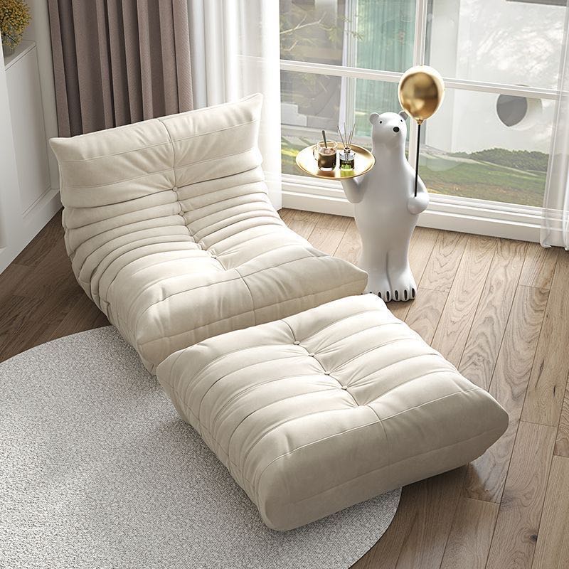 Togo Fireside Chair and Foot Stool in modern living room, suede upholstery, elegant design.